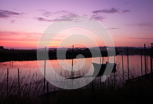 Amazing shot of a colorful sunset with a reflecton on the water and a fishing boat photo