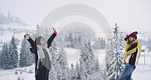 In amazing snowy forest and mountain two friends one lady and man taking pictures in a beautiful place on the top of