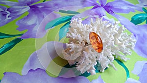 The amazing sparkling amber ring is located on a natural white coral placed on a purple silk fabric.