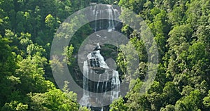 Amazing summer landscape with forest river waters falling down in big waterfall with clear water between rocky boulders