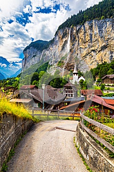 Amazing summer landscape of touristic alpine village Lauterbrunnen with famous church and Staubbach waterfall. Location: