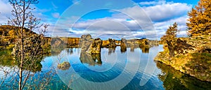 Amazing sunny day on lake Myvatn, Iceland, Europe. Volcanic rock formations reflected in the blue clear water of a volcanic lake.