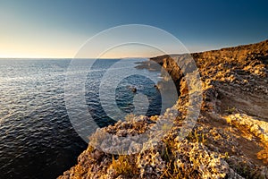 Amazing sunrise over the rising cliffs and rocks in Malta, with spectacular colors in the sky and reflections of the sun in het Me