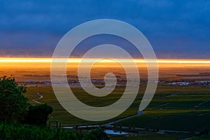 Amazing sunrise on rainy day over green grand cru vineyards near Epernay, region Champagne, France. Cultivation of white