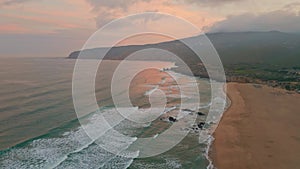 Amazing sunrise sea shore aerial view. Foamy waves rolling to sandy empty beach