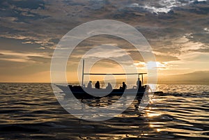 Amazing sunrise with silhouette of people in small boat in Lovina, Bali