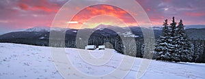 Amazing sunrise. Winter forest. Old wooden huts on the lawn covered with snow. High mountains with snow white peaks. Wallpaper