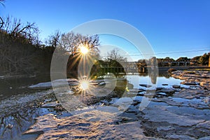 Amazing sunset landscape at Bushy Creek in Round Rock, Texas. Sun and Stones are reflected in water with blue sky.