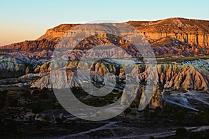 Amazing sunset landscape view of typical geologic formations of Cappadocia. Mountain in the sunset light in the background.