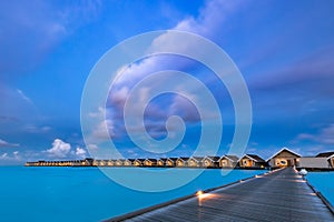 Amazing sunset at Maldives. Luxury resort villas seascape with soft led lights under colorful sky. Beautiful twilight sky