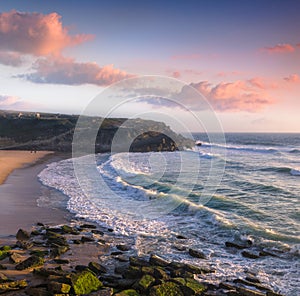 Amazing sunset on the ocean. View of dramatic cloudy sky and stony coast. Portugal.