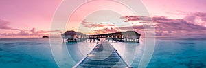 Amazing sunset panorama at Maldives. Luxury resort villas seascape with soft led lights under colorful sky