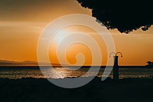 Amazing sunset seascape. Beach shower and orange sky. Brela Croatia, Makarska riviera