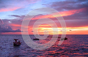 During an amazing sunset, a view from the Nightcliff jetty, Darwin, NT Australia, of two small boats sailing on the sea.