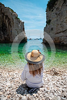 Amazing symmetrical view of a brunette from behind, Stiniva beach on the island of Vis in Croatia. Crystal clear green teal sea,