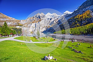 Amazing tourquise Oeschinnensee with waterfalls, wooden chalet and Swiss Alps, Berner Oberland, Switzerland