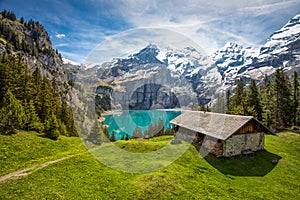 Amazing tourquise Oeschinnensee with waterfalls, wooden chalet and Swiss Alps in Berner Oberland