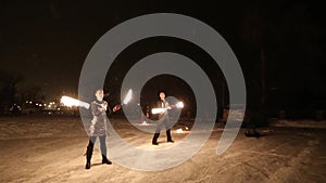 Amazing tribal fire show dance at night on winter under falling snow. Dance group performs with torch lights and