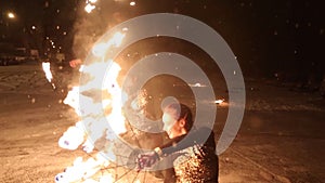 Amazing tribal fire show dance at night on winter under falling snow. Dance group performs with torch lights and