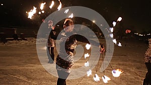 Amazing tribal fire show dance at night on winter under falling snow. Dance group performs with torch lights and