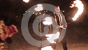 Amazing tribal fire show dance at night on winter under falling snow. Dance group performs with torch lights and