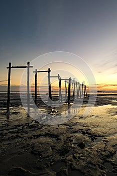 Amazing tropical sunset background, wooden structure on the muddy beach