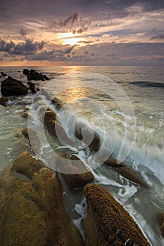 Amazing twilight Sunset seascape with sea wave hitting the green moss