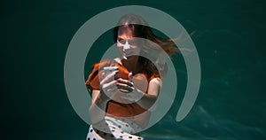 Amazing under water portrait of happy excited successful young woman reacting to great news on smart phone slow motion.