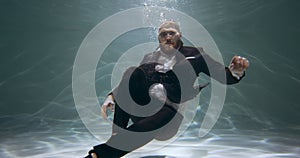 Amazing under water portrait of happy young positive businessman in office suit showing OK gesture at camera slow motion