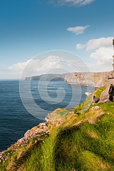 Amazing view on Cliff of Moher, county Clare, Ireland. Popular landmark with unparalleled scenery. Warm sunny day, Cloudy sky.