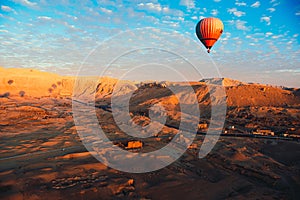 Amazing view from a luxor hot air balloon, one single orange balloon in the air over the desert area. Valley of the kings and