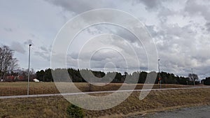 Amazing view over spring forest with green trees on blue sky with white clouds background. Green yellow trees and road.