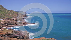 Amazing view of the rocky coast of Oahu Hawaii. The turquoise waves of the Pacific Ocean wash over volcanic rocks