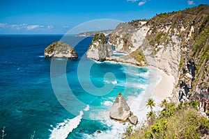 Amazing view of a secret beach with coconut palms and rocks in Nusa Penida, Bali