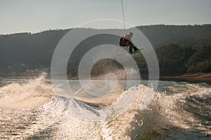 amazing view of the splashing wave and active man jumping in the air with wakeboard