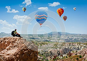 Amazing view with sport sitting girl and a lot of hot air balloons. National park Anatolia, Cappadocia, Turkey. Artistic picture photo