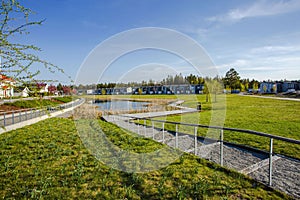 Amazing view of suburbian landscape. Path to little pond and cute compact suburbian houses on blue sky background. photo