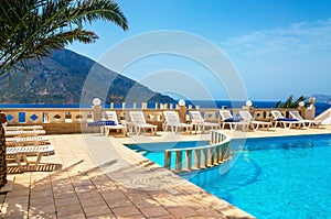 Amazing view on swimming pool area and sunbeds under palm tree w