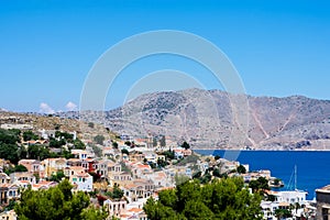 Amazing view on tiny colorful houses on rocks and oleander trees near the Mediterranian sea on Greek island in sunny summer day photo
