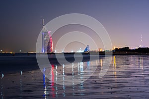 Amazing view to the illuminated Burj al Arab, luxury and modern hotel in Dubai. Colorful lights reflects over the water.