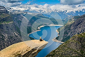 Amazing view with Trolltunga and a girl sitting on it. Norway