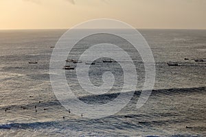 Amazing view of Uluwatu Beach, where surfers and fishermen meet in the sea on dusk, Uluwatu, Bali, Indonesia