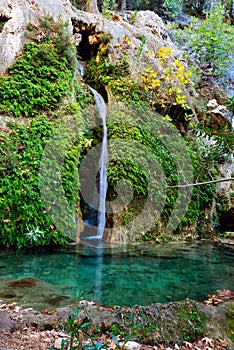 Amazing waterfall flows along the cliff into a small lake