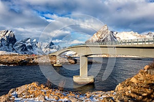 Amazing winter landscape, Lofoten Islands, Norway. Scenic view of the snowy rocky mountains, bridge, water and blue sky with cloud