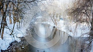 Amazing winter landscape in the public park. Scenic view of the river and reflection of frosty trees in the water. Panorama nature
