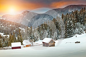Amazing winter sunset with snowy rural wooden chalets, Transylvania, Romania