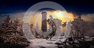 Amazing winter view of frosted trees and rock at sunrise, frozen lookout tower Sneznik, Bohemian Switzerland