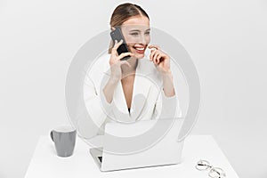 Amazing woman posing  over white wall background using laptop computer talking by mobile phone