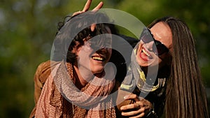 Amazing Woman with Short Curly Hair is Carrying Her Female Friend in Sunglasses on the Shoulders.Two Attractive