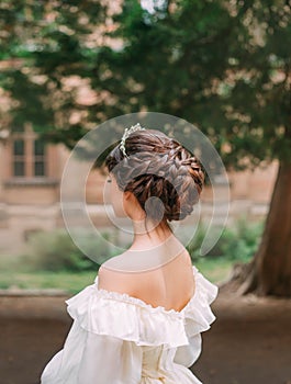 Amazing work of professional hairdresser, gentle hairstyle of long dark brown hair and tiara for prom or evening